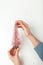 Closeup of a woman& x27;s hands holding a small pink shimmering decorative Christmas tree, flatlay