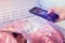 Closeup of woman`s hands scanning QR Code of meat products in the freezer with smart phone in supermarket