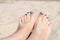 Closeup on woman sandy feet with blue nails pedicure