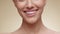 Closeup of woman smiling to camera, showing white smile of after teeth alignment procedure, beige background