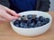 Closeup of woman spooning fresh blueberries out of a white bowl
