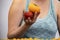 Closeup of woman in tank top holding two heirloom tomatoes in her hand at farmers market - unrecognizable