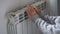 Closeup of woman warming her hands on the heater at home during cold winter days. Heating season.