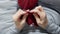 Closeup womans hands knitting red burgundy wool yarn.