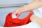 Closeup womans hands putting red clothing into washing machine, laundry housework concept