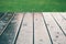 Closeup of wood planks while raining in perspective with grass at the top. Background of wooden natural surface and raindrops