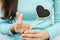 Closeup wooden black board in heart shape with finger of woman in mini heart symbol