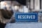 Closeup wooden blue white rectangular plate with the word Reserved standing on gray table in restaurant. Ð¡oncept of preparation