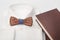 Closeup of wooden bow tie on the white classic shirt with brown notebook light background