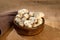 Closeup of a wooden bowl overflowing with mushrooms on a rustic wooden table surface