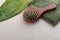 Closeup of wooden brush, green topical leaf and towel on the empty beige surface