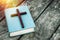 Closeup of wooden Christian cross on bible, burning candle and prayer beads on the old table.