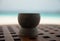 Closeup of wooden cup on wooden table with beach in background