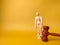 Closeup of a wooden mannequin and gavel on a yellow background with copyspace - Law concept