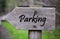 Closeup of a wooden sign with the [parking] word written on it against a blurry background