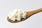 Closeup of wooden spoon and delicious cottage cheese against bright background