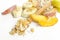Closeup of wooden spoon full of corn flakes, oatmeal, slices of peach, banana, plum on the white surface.Tasty fruity breakfast