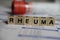 Closeup of word rheuma on laboratory requisition slip with syringe and vial selective focus on text blocks in center