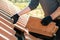 Closeup of worker hands installing yellow ceramic roofing tiles mounted on wooden boards covering residential building roof under