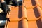 Closeup of worker hands installing yellow ceramic roofing tiles mounted on wooden boards covering residential building roof under