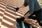 Closeup of worker hands installing yellow ceramic roofing tiles mounted on wooden boards covering residential building roof under