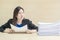 Closeup working woman are boring from pile of work paper in front of her in work concept on blurred wooden desk and wooden wall te