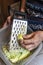 Closeup wrinkled hands grating the zucchinis in kitchen