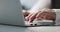 Closeup of the wrinkled hands of an old business woman typing on a keyboard.