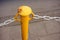 Closeup of a yellow metal pole with attached chain barrier
