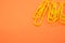 Closeup of yellow paperclips on orange background with space for your text