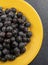 Closeup of a yellow plate of blueberries on a blue background