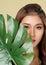 Closeup young ardent woman with healthy skin holding green leaf near her face.