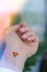 Closeup of young caucasian millennial hippie woman with a rainbow flag in heart shape painted in wrist. Rainbow color