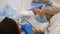 Closeup of young dentist in protective mask and glasses curing tooth cavity.