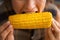 Closeup on young housewife eating boiled corn