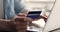 Closeup young male hands hold credit card type on laptop