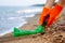 Closeup of young male volunteer`s hands picks up plastic garbage on the ocean coast. A man collects waste on the seaside to save