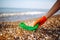 Closeup of young male volunteer`s hands picks up plastic garbage on the ocean coast. A man collects waste on the seaside to save