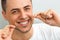 Closeup of young man flossing his teeth. Cleaning teeth with den