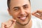 Closeup of young man flossing his teeth. Cleaning teeth with den