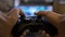 Closeup of young man hands playing video games on gaming console in front of TV widescreen -