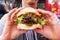 Closeup of a young man holding a tasty vegan burger in his hands