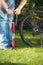 Closeup of young man pumping bicycle wheel on grass