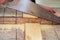 Closeup of a young man sawing a wooden board with a handsaw