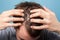 Closeup of young man showing clean scalp and washed brown healthy hair. indoor studio shot isolated on blue background