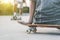 Closeup of young man sitting on skateboard looking his friend training outdoor - Skateboarder preparing to jump in urban contest