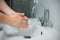 Closeup of a young man washing his hands with soap in the sink of a bathroom. Coronavirus Covid 19 Prevention.