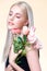 Closeup young personable woman with flawless makeup holding flower.