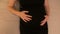 Closeup of a young pregnant expectant mother dressed in black dress lying on the bed massaging her belly