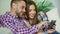 Closeup of young smiling couple using tablet computer for surfing internet and chatting sit on couch in living room at